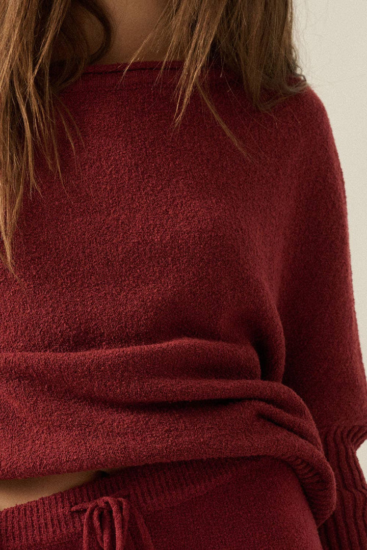 Close-up of a woman wearing a burgundy sweater with a neutral background