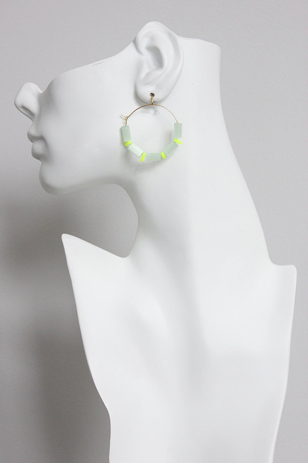 Hoop earring with sea green beads displayed on a mannequin bust against a gray background