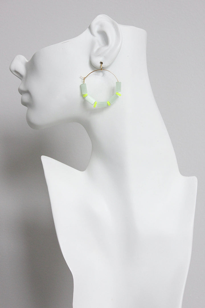 Hoop earring with sea green beads displayed on a mannequin bust against a gray background
