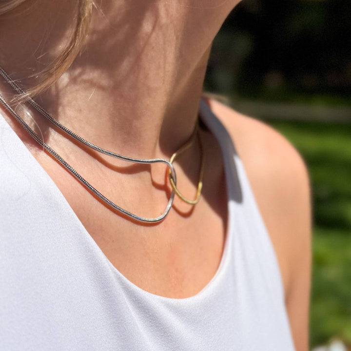 Close up of a woman wearing a mixed metal necklace.
