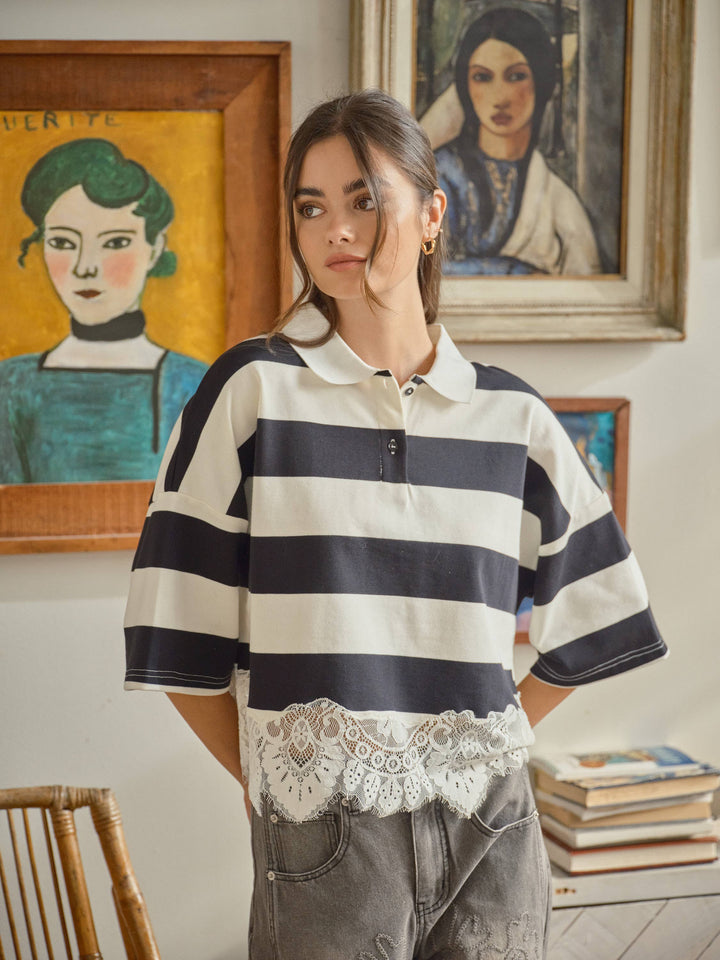 Woman wearing a striped polo shirt with lace details in an art-filled room.