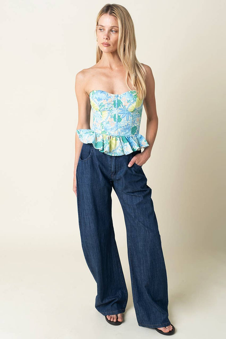 Woman wearing a floral top and blue jeans against a plain background