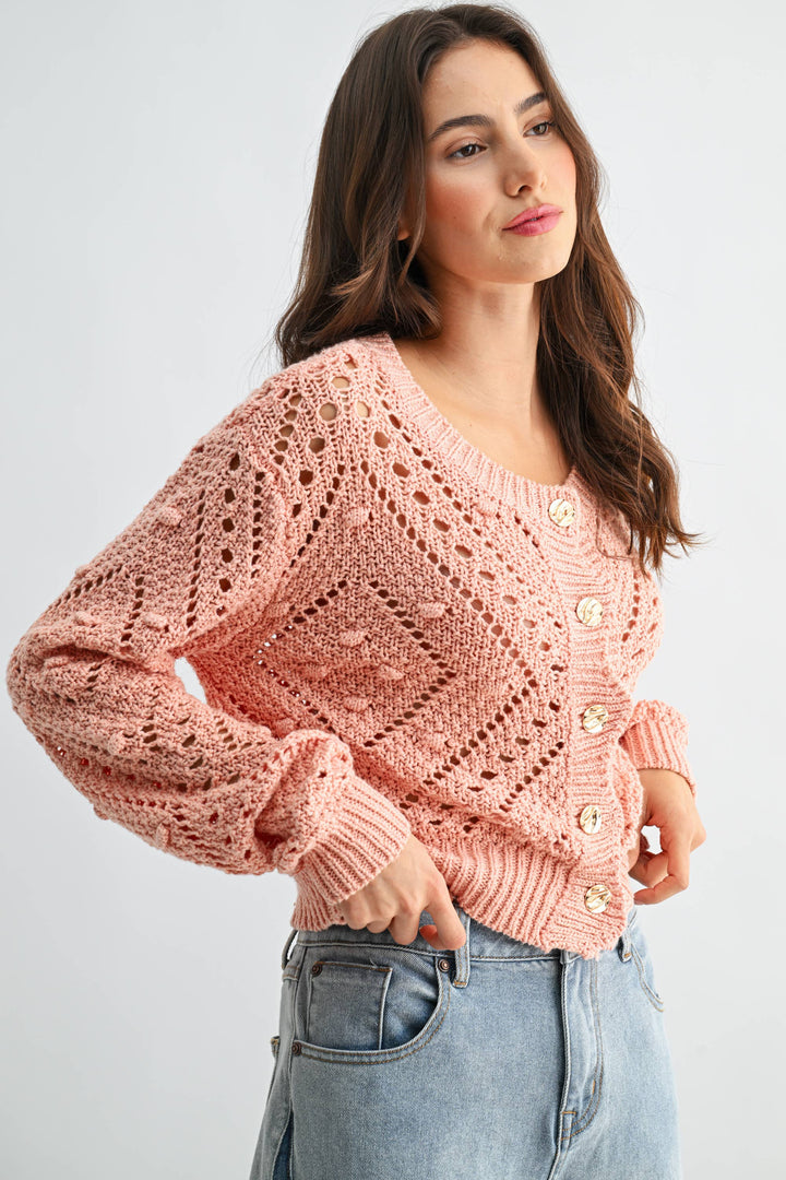 Woman wearing a pink knitted sweater with buttons on a light gray background