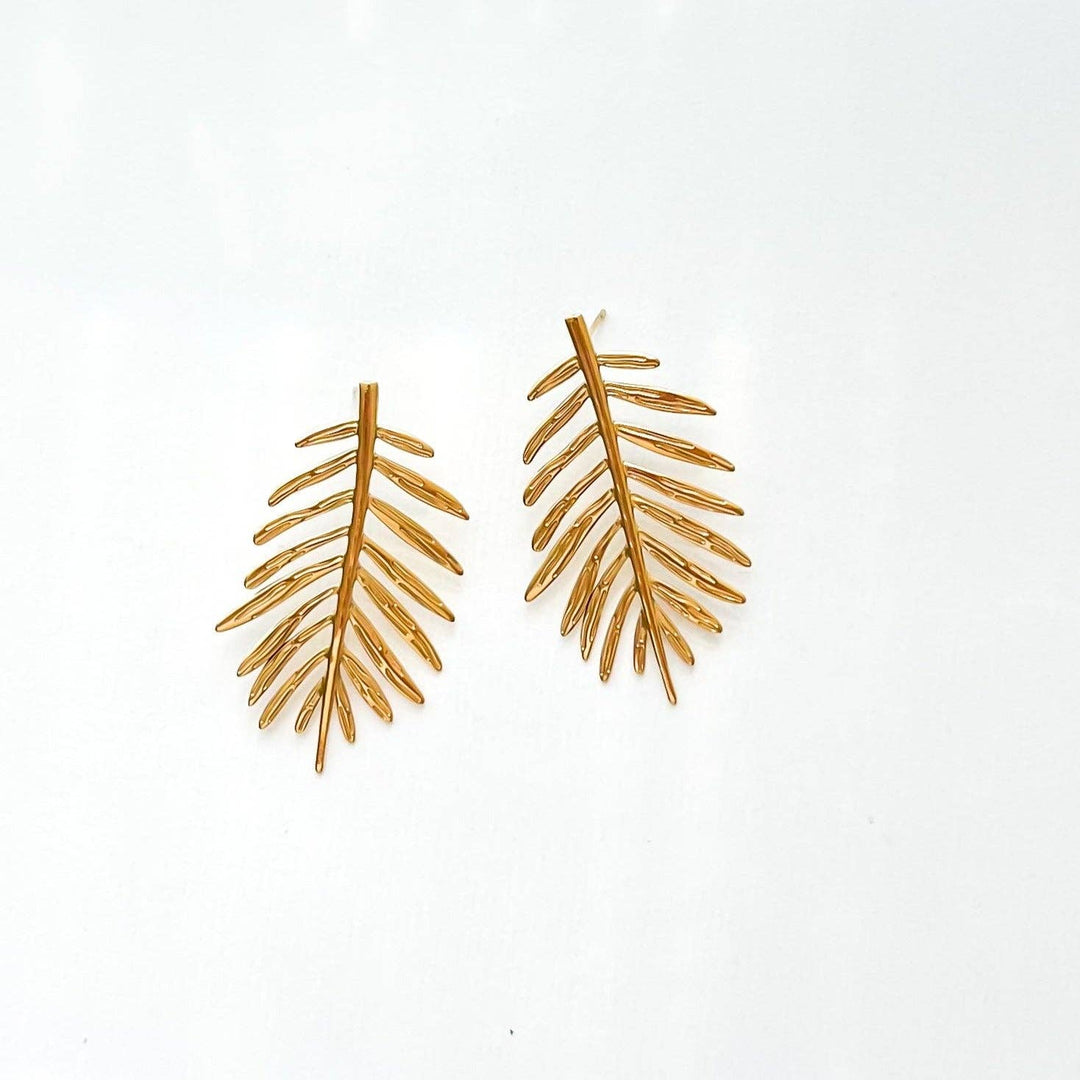Gold leaf-shaped statement earrings on a white background