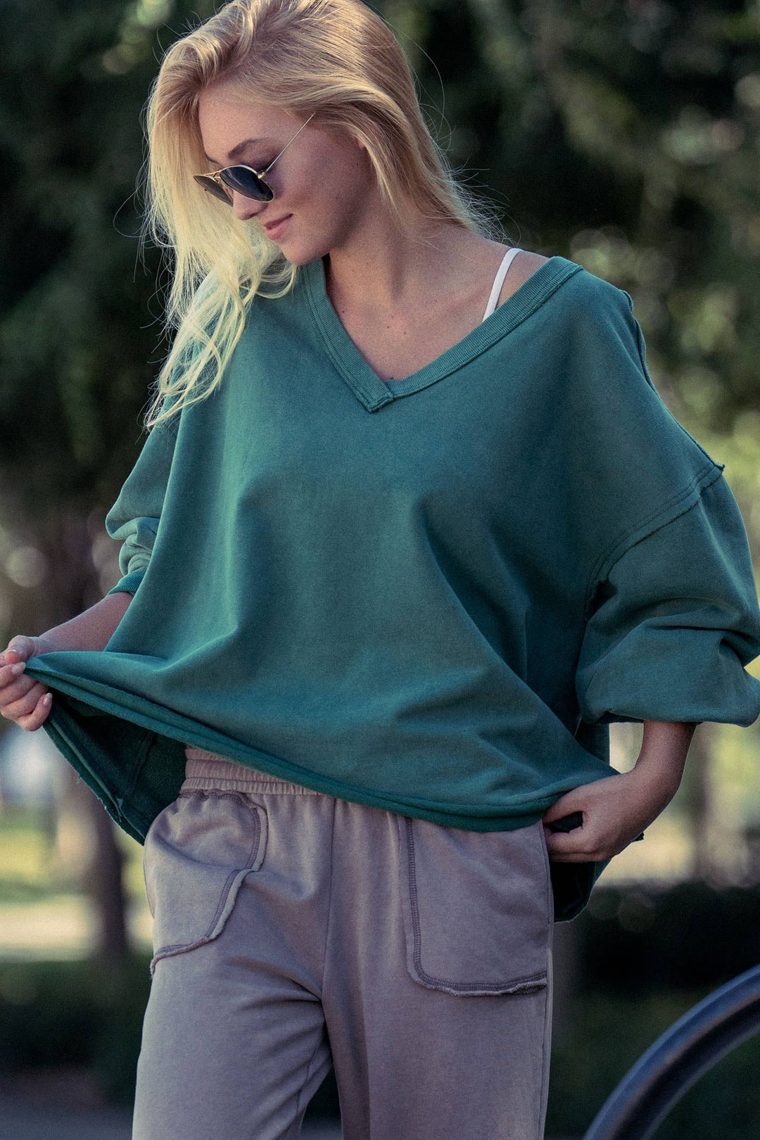Woman wearing a teal sweater and gray pants outdoors