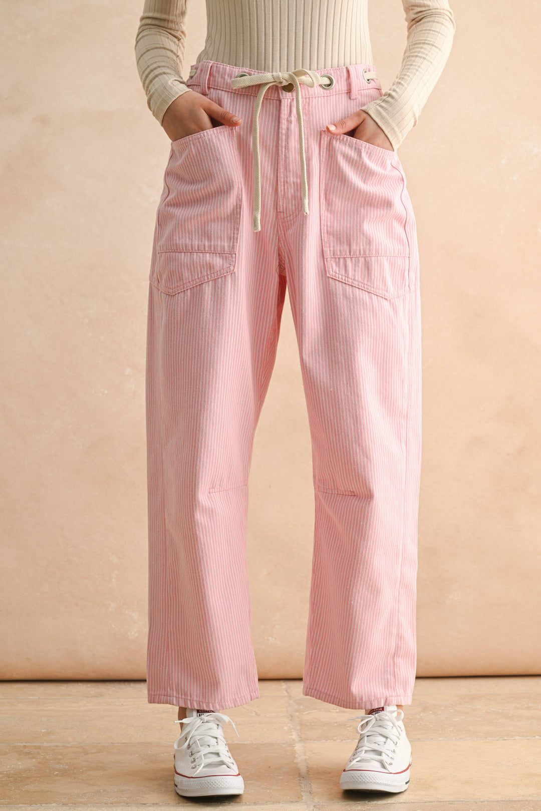 Person wearing pink striped pants drawstring waist and barrel leg 