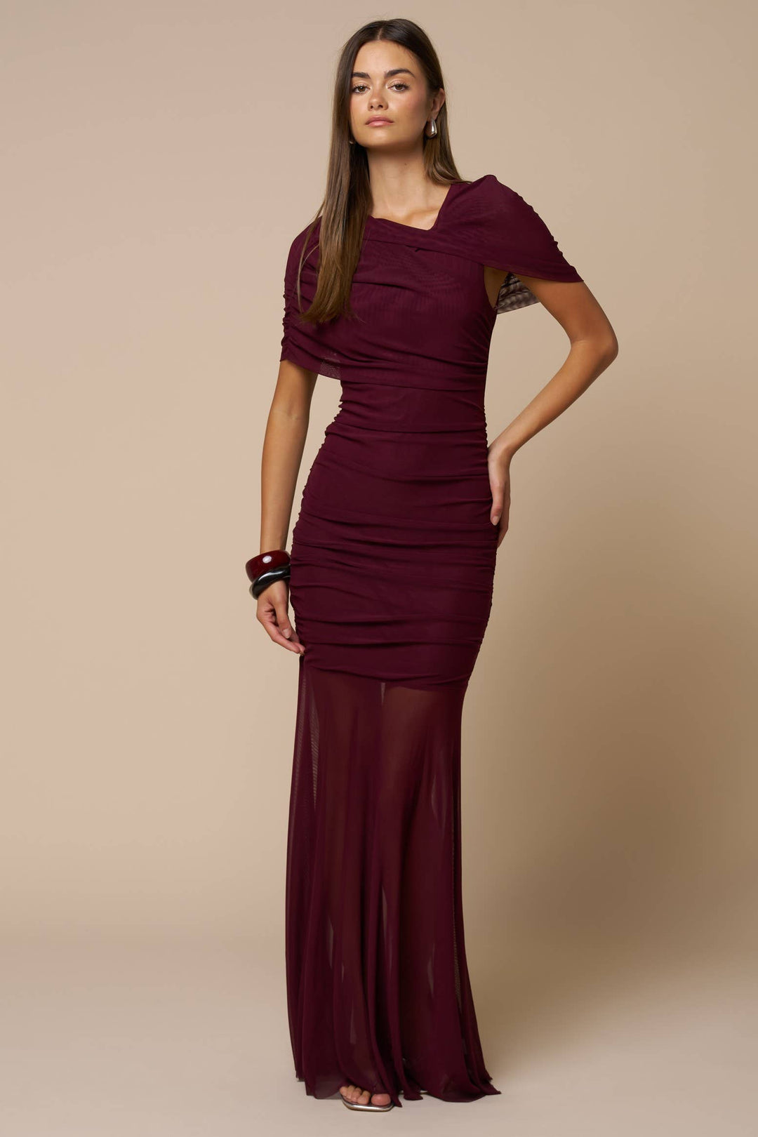 Woman wearing a burgundy evening gown against a beige background