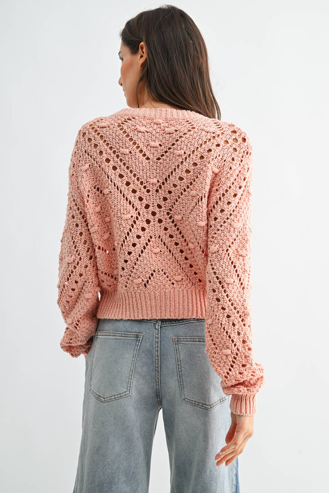 Woman wearing a pink knitted sweater with a white background