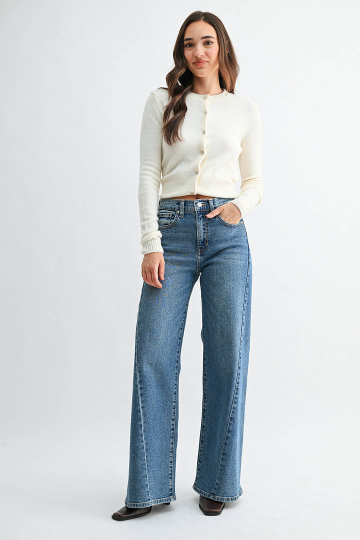 Woman wearing medium wash blue wide leg jeans with seam detail on a white background