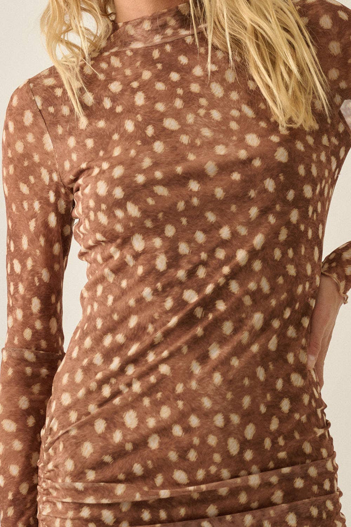 A close-up of a woman wearing a brown long-sleeve mock-neck top with a beige bambi print pattern, showing the ruched side details and her blonde hair.