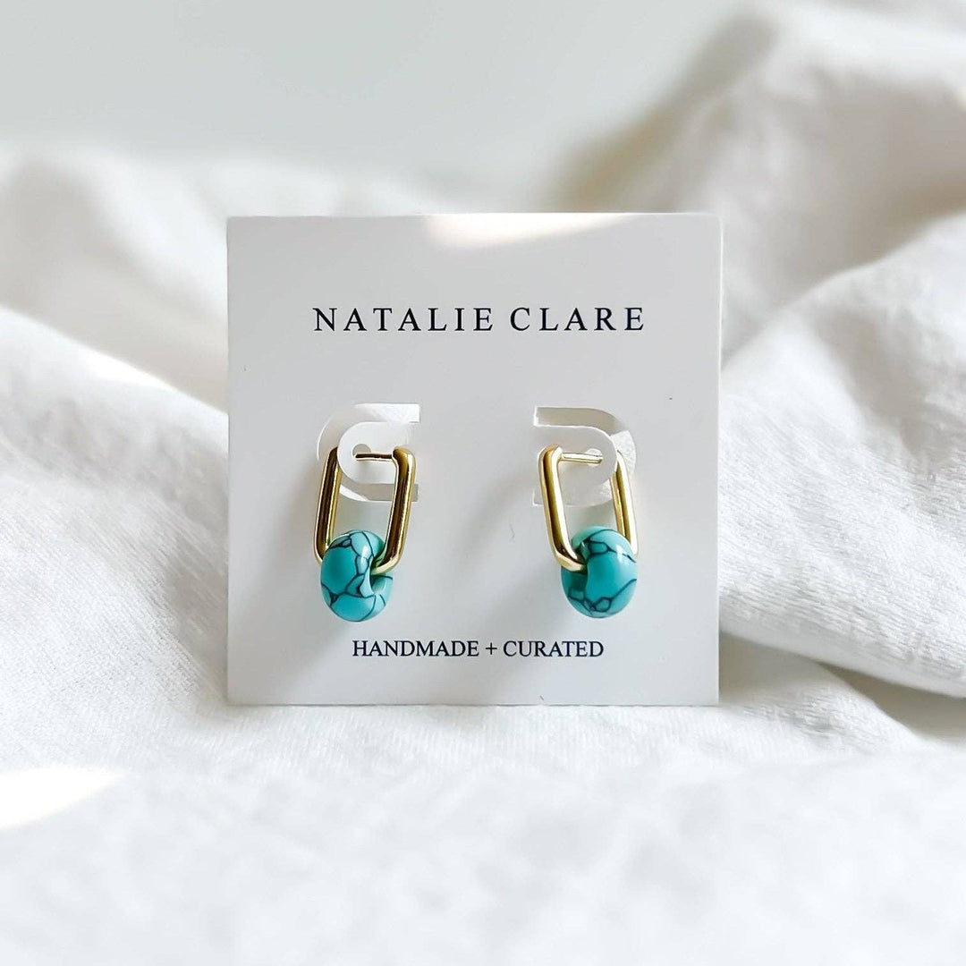 Turquoise and gold hoop earrings on a 'Natalie Clare' branded card with white fabric background