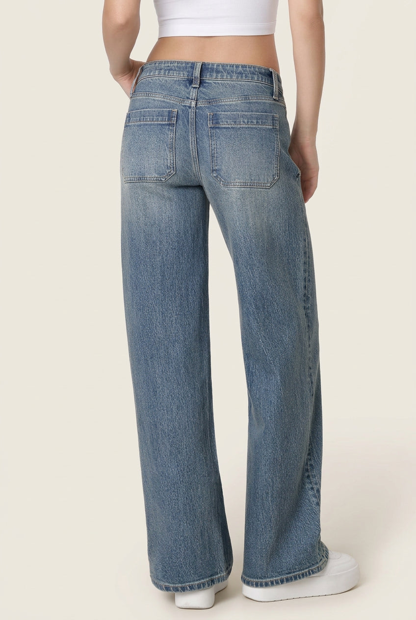 A person shown from the back wearing light blue wide-leg denim jeans, a white crop top, and white sneakers against a plain white studio background.