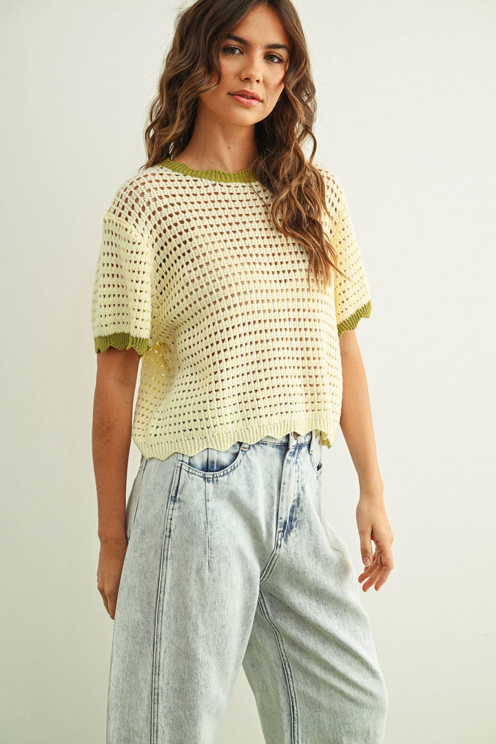 Woman wearing a white crochet top and light blue jeans on a plain background
