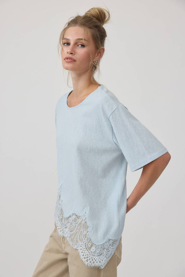 Light blue t-shirt with lace detail worn by a model on a white background
