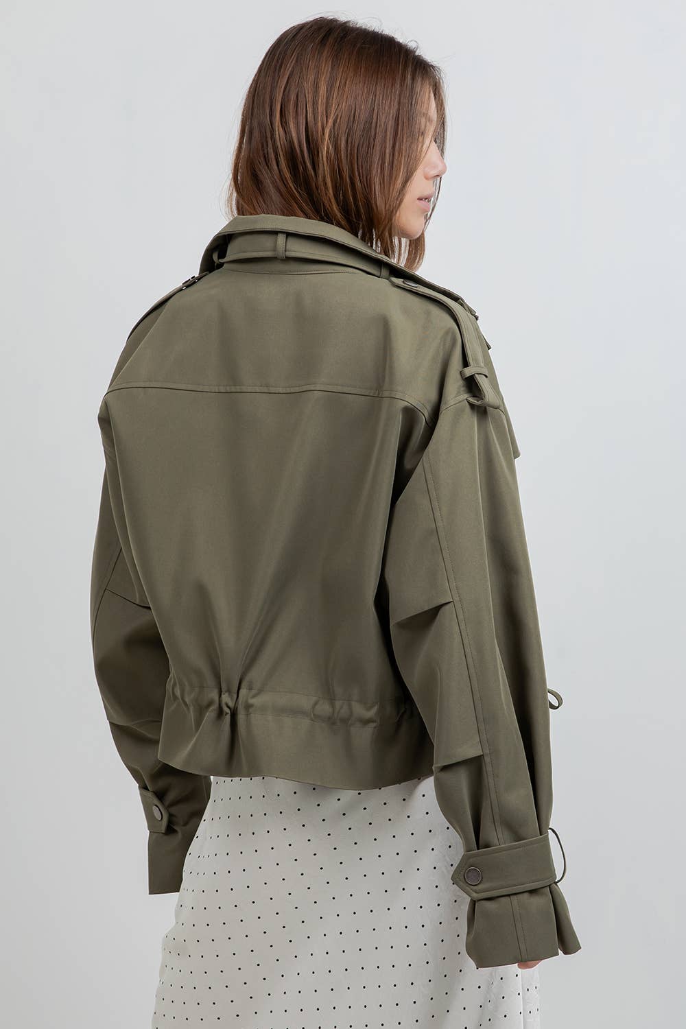 Woman wearing an olive green jacket on a white background
