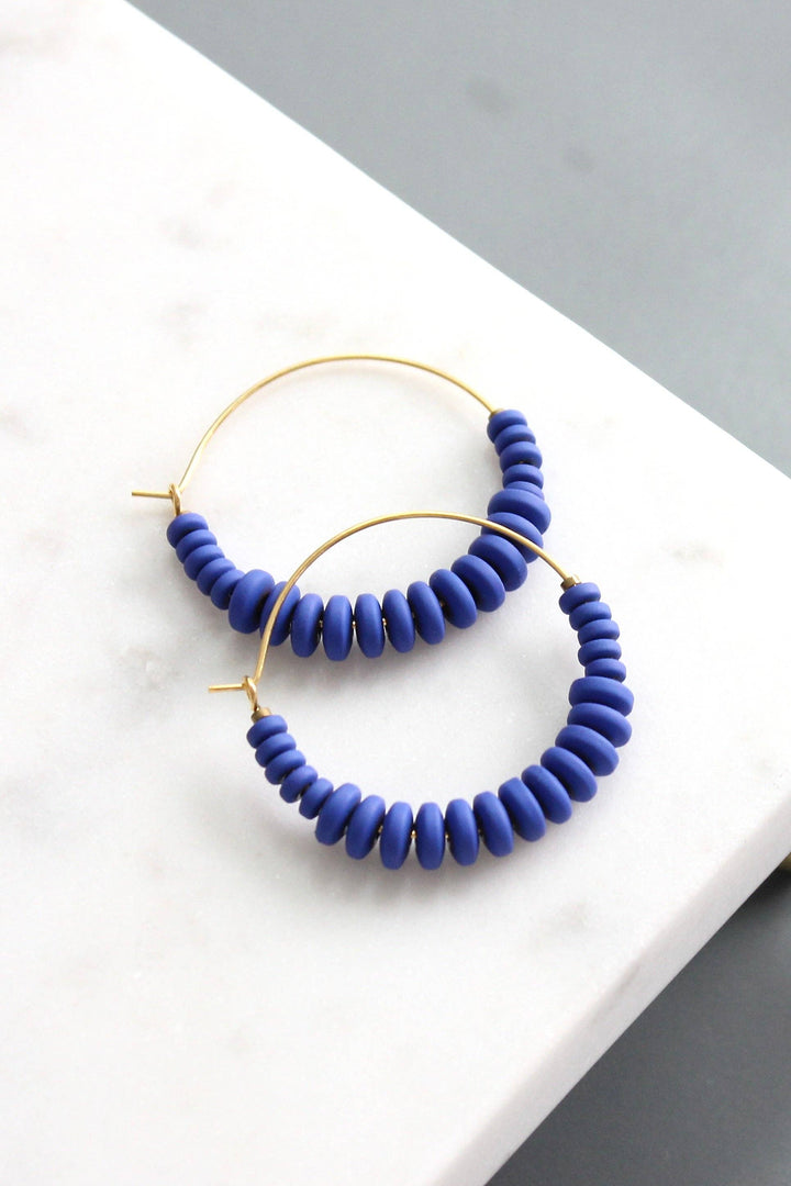 Pair of blue beaded hoop earrings on a white surface