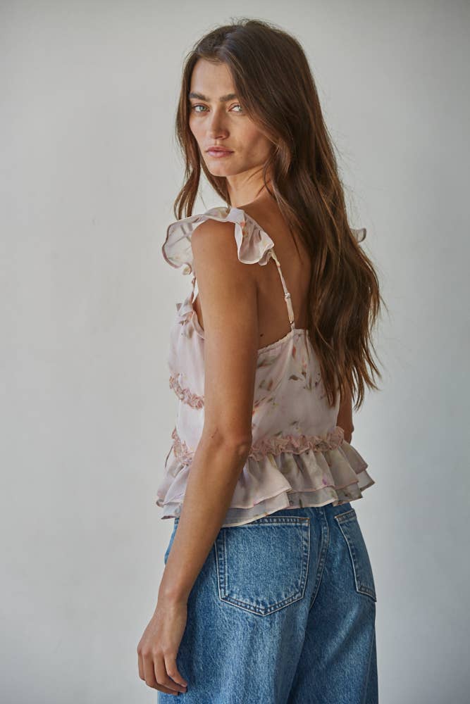Woman wearing a pink floral top and blue jeans against a plain background