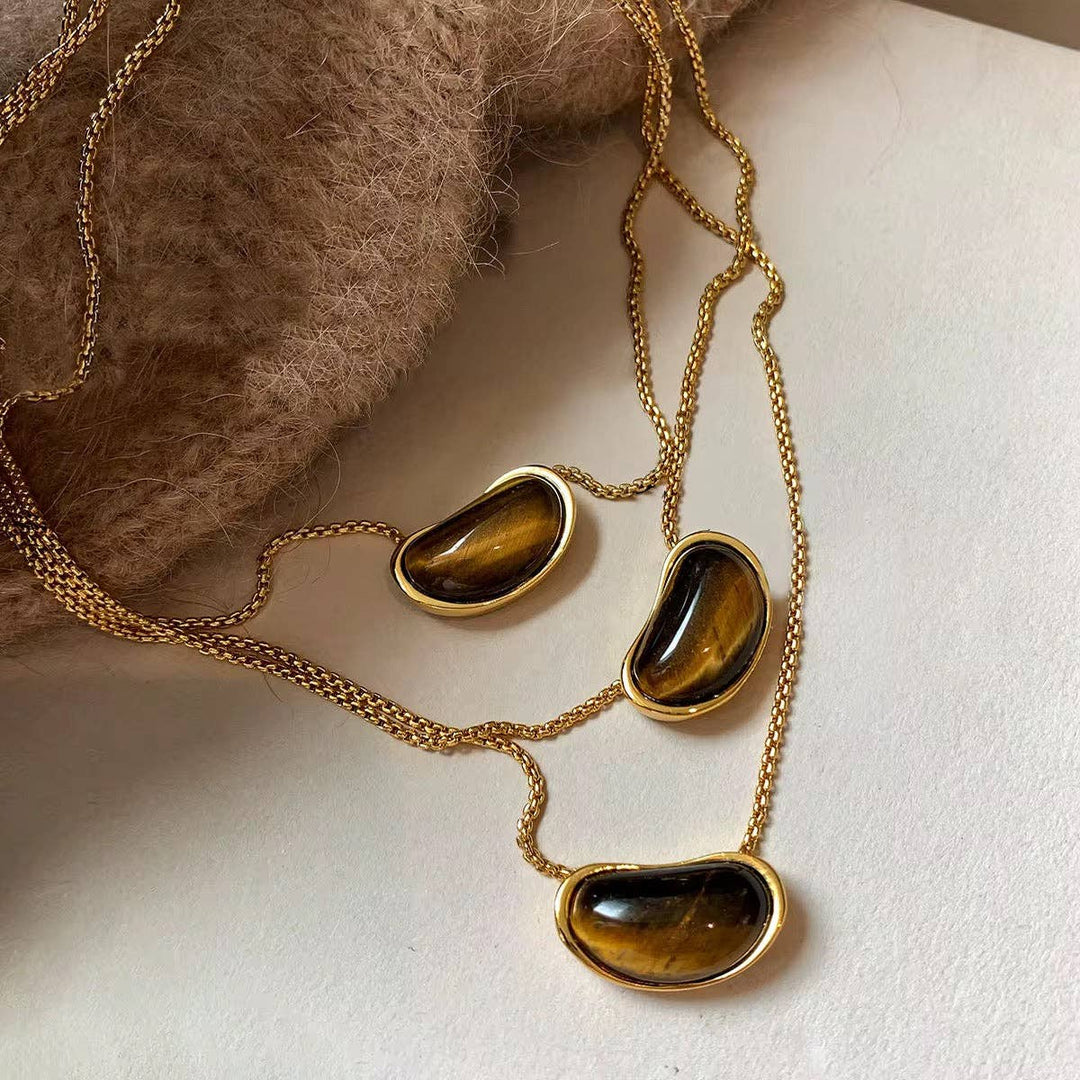 Gold necklace with tiger's eye stones on a neutral background