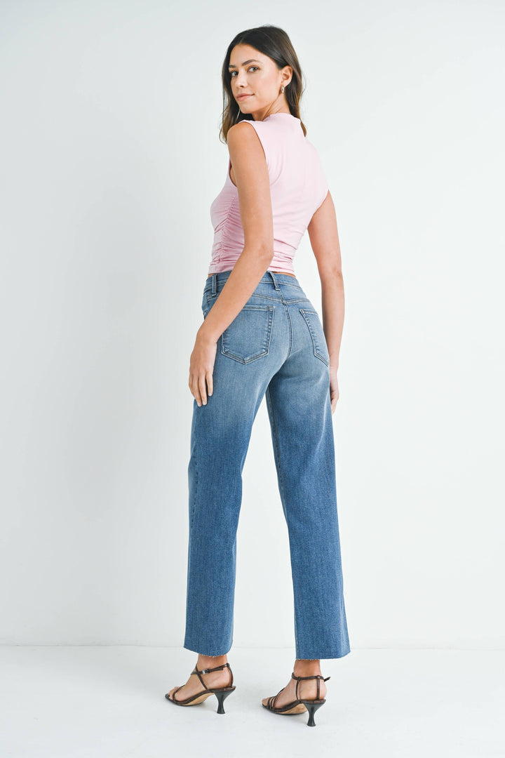 Woman wearing a pink sleeveless top and blue jeans on a white background
