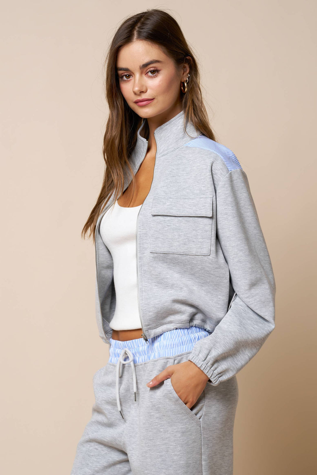 Woman wearing a gray lounge wear matching set outfit with a beige background