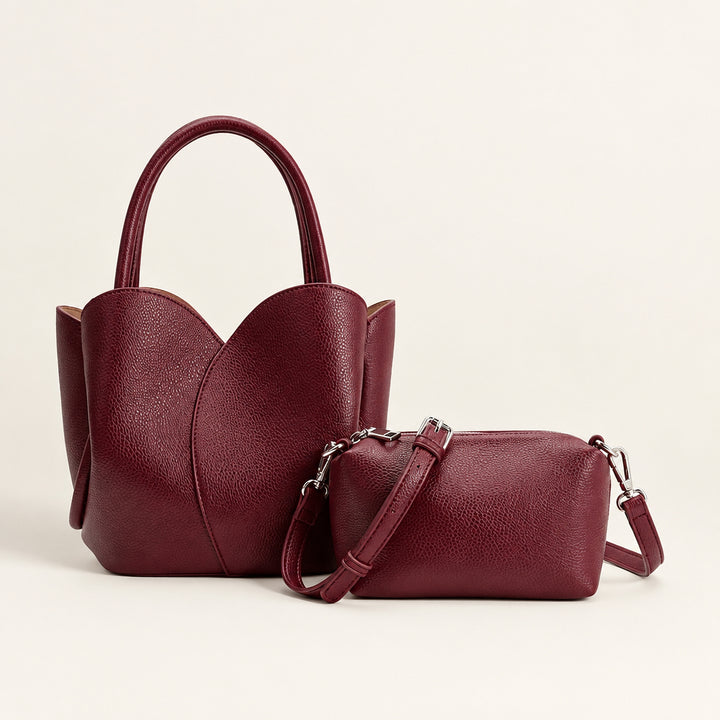 Two maroon handbags, one with a shoulder strap and the other with handles, on a white background.