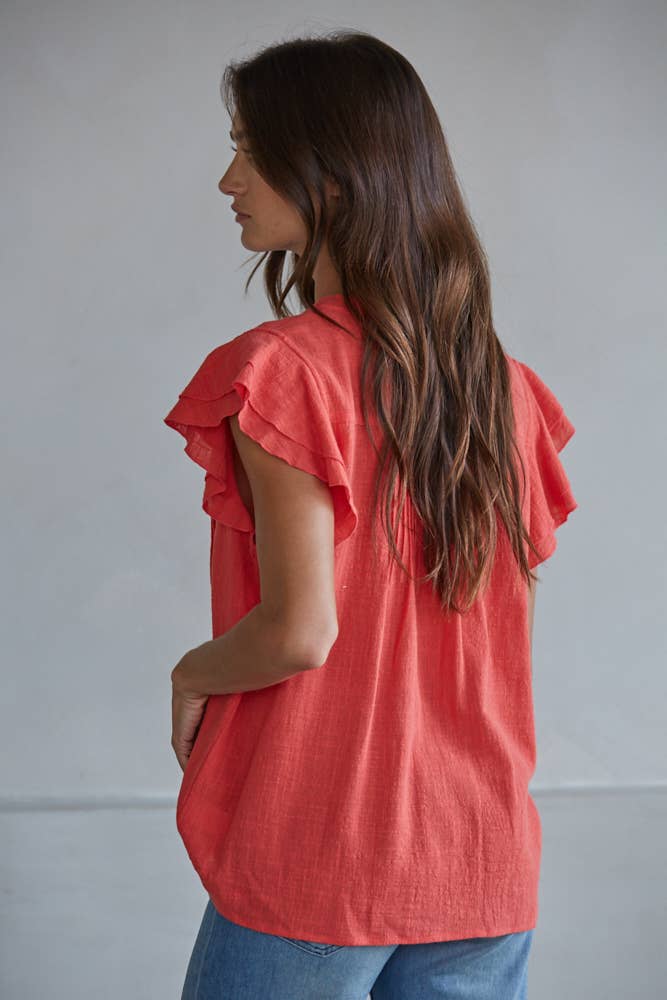 Woman wearing a red ruffled blouse against a plain background