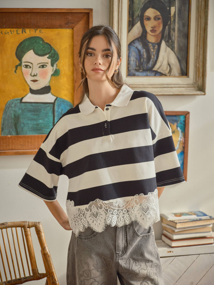 Person wearing a black and white striped shirt with lace details in an art-filled room.