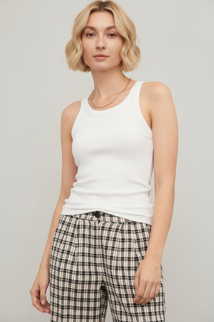 Woman wearing a white tank top and plaid pants against a plain background