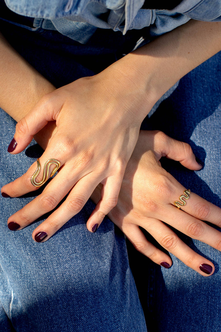 Close-up of hands wearing gold rings with a denim background