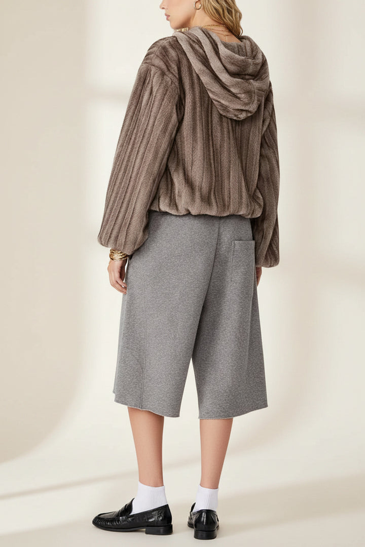 A model shown from the back wearing a brown ribbed knit hooded cardigan, gray cropped knit shorts, white socks, and black loafers, against a plain white background.