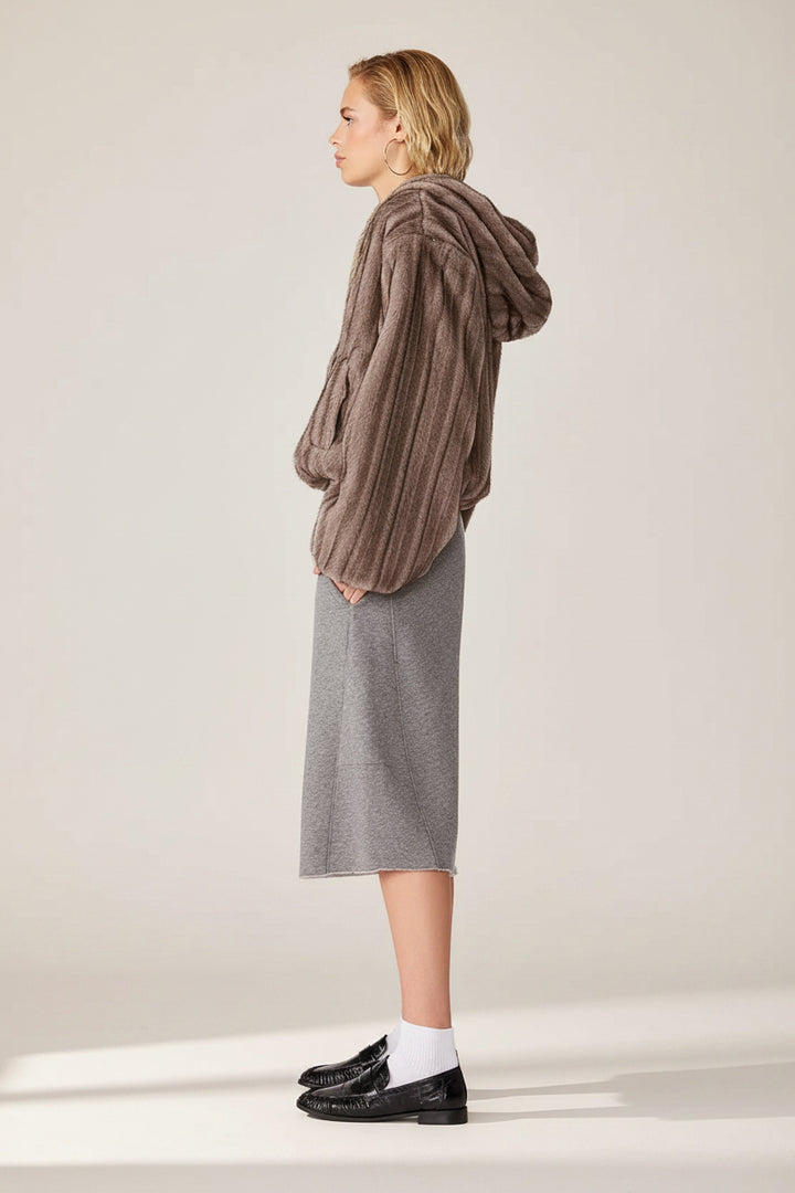 A model shown from the side profile wearing a brown ribbed knit hooded sweater, a gray midi skirt, white socks, and black loafers against a plain white background.