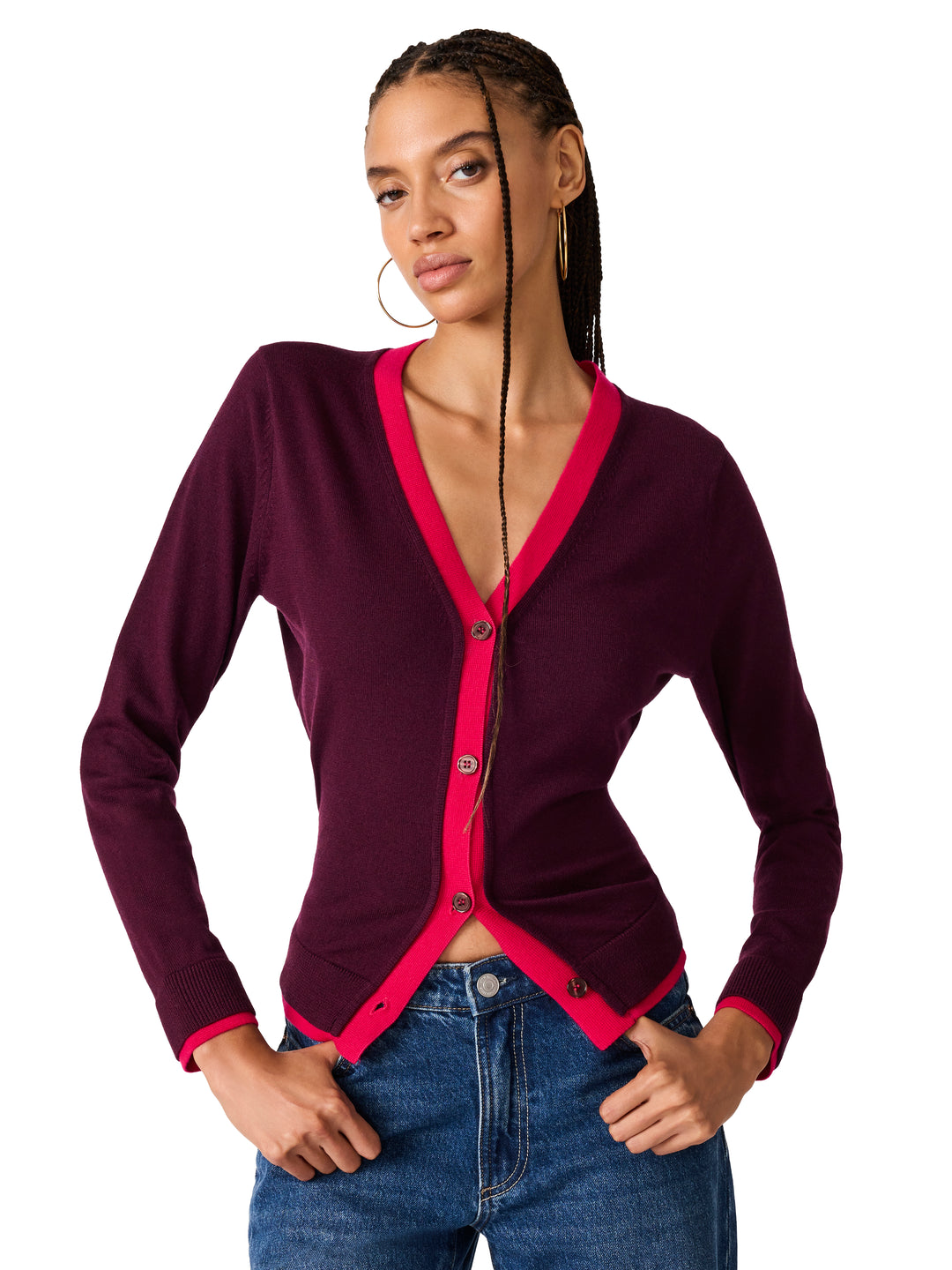 A woman modeling a long-sleeve cardigan with a deep burgundy body and bright pink trim, paired with blue jeans against a plain white background.