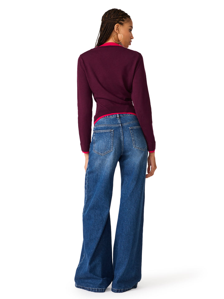 A woman shown from the back wearing a plum colored long-sleeve cardigan, blue wide-leg jeans. She is photographed against a clean white background.