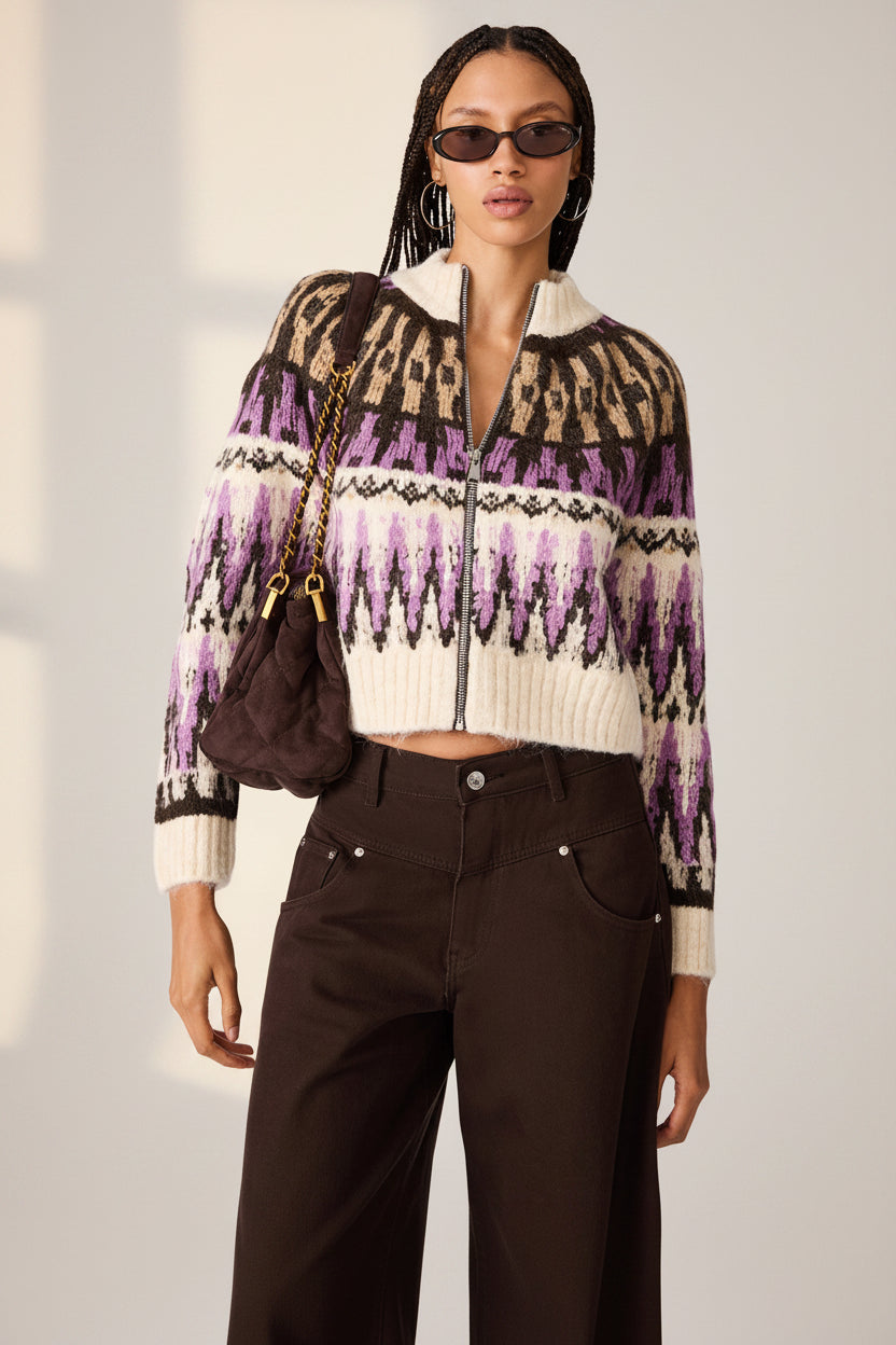 A model wearing a cropped knit zip-up cardigan with a brown, cream, and purple Fair Isle pattern, paired with dark brown pants and sunglasses.