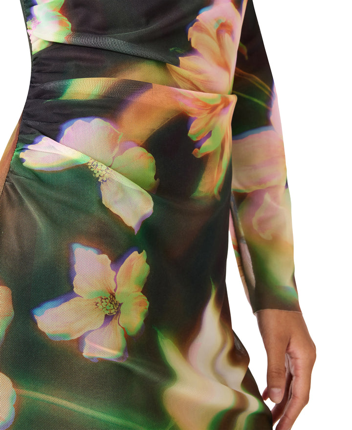 A close-up of a long-sleeve dress featuring a dark base with a vibrant, iridescent floral print in pink, green, and yellow tones, shown on a model against a white background.