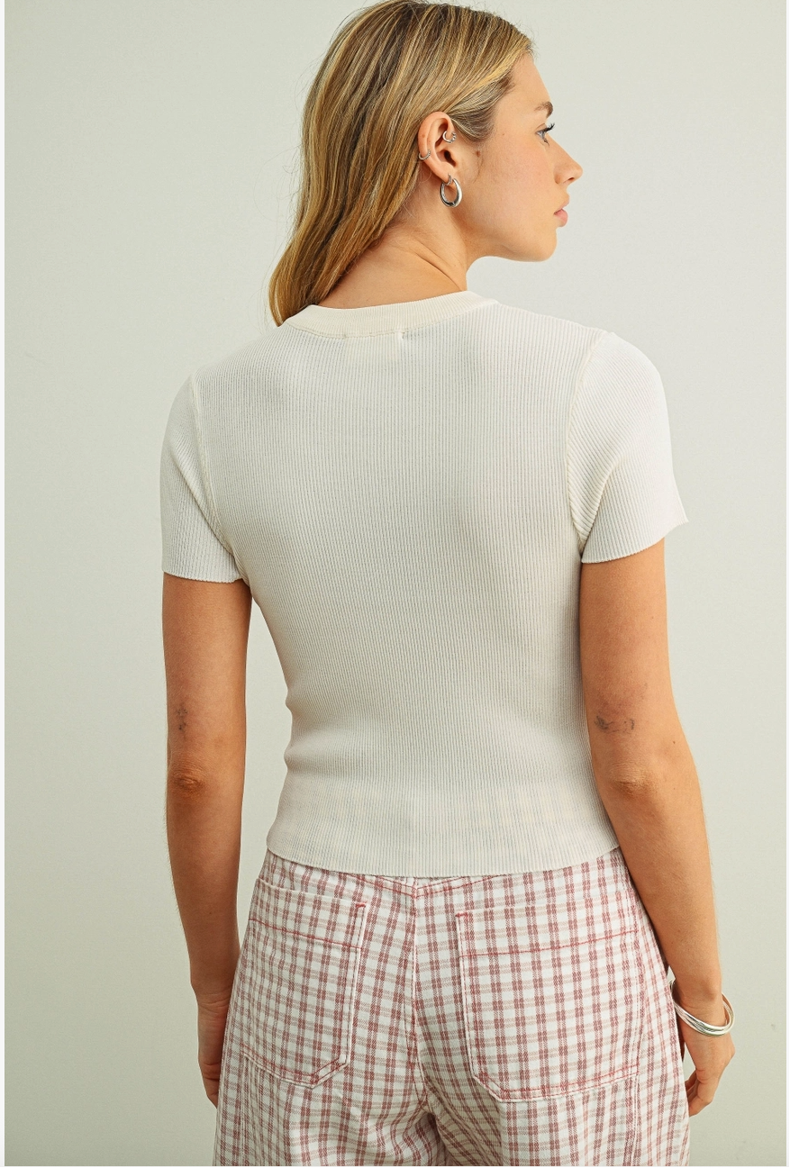 Woman from behind wearing a fitted short-sleeve cream top and a pink-and-white gingham skirt. 