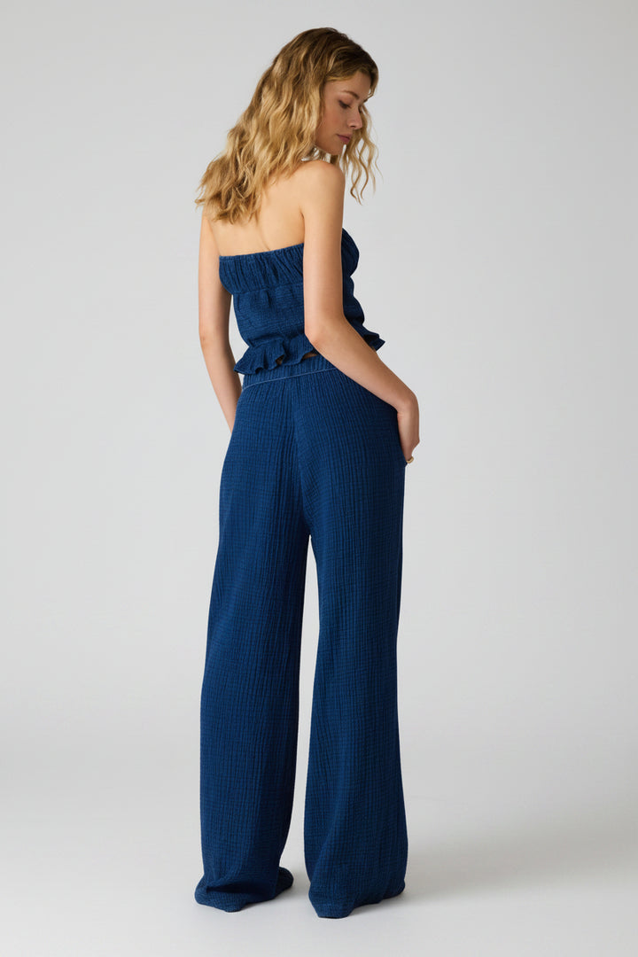 Woman wearing a blue strapless peplum top and wide leg pants as a matching set 
