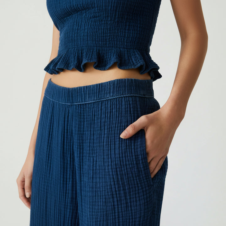 Close-up of blue ribbed pants with a hand in the pocket on a white background