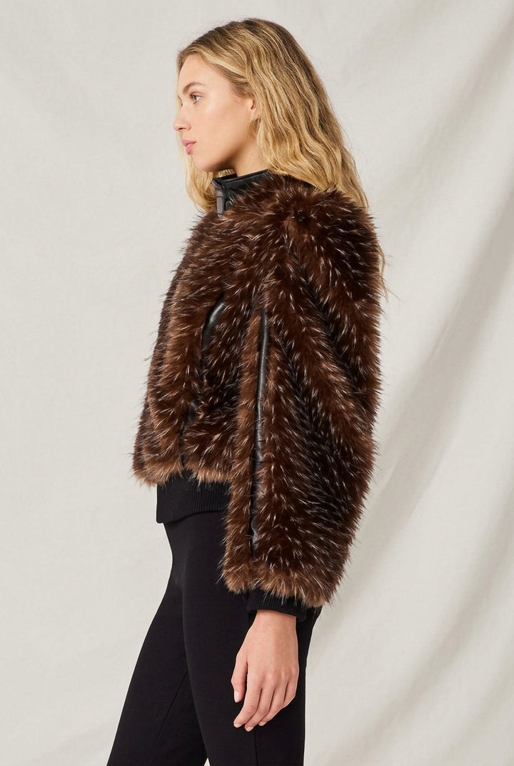 Woman wearing faux fur dark brown jacket with black faux leather trim.