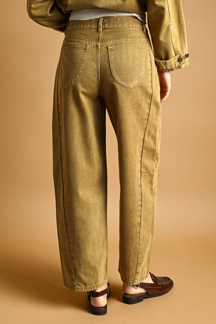 Woman wearing khaki barrel jeans on a beige background