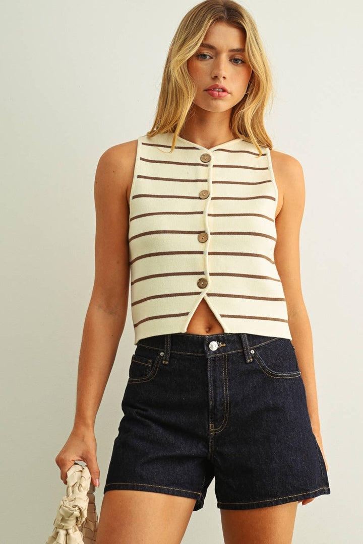 Woman wearing a striped sleeveless top and denim shorts against a plain background