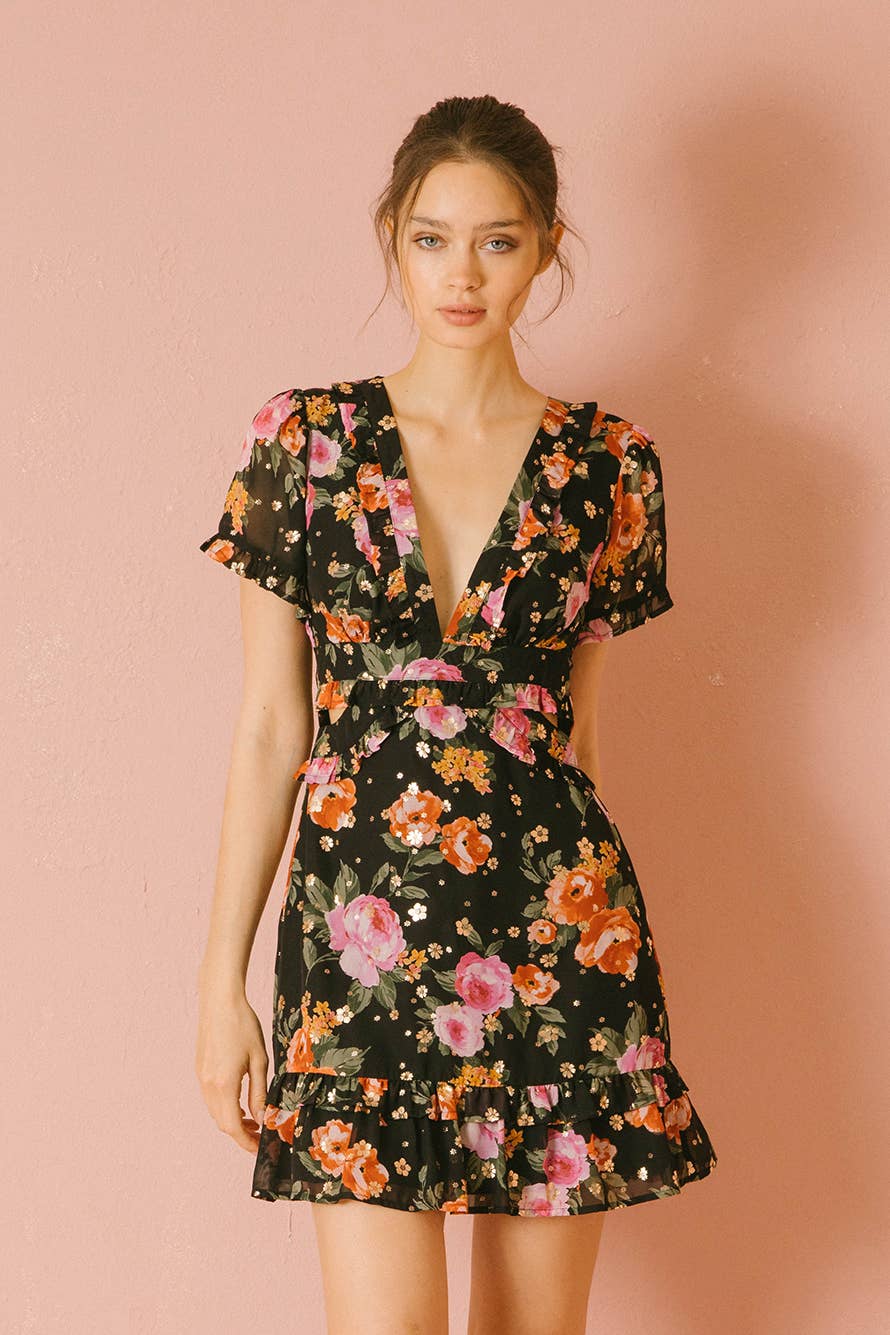 Woman wearing a black floral mini dress against a pink background