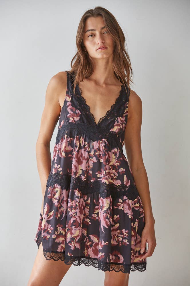 Woman wearing a floral dress with lace details against a plain background
