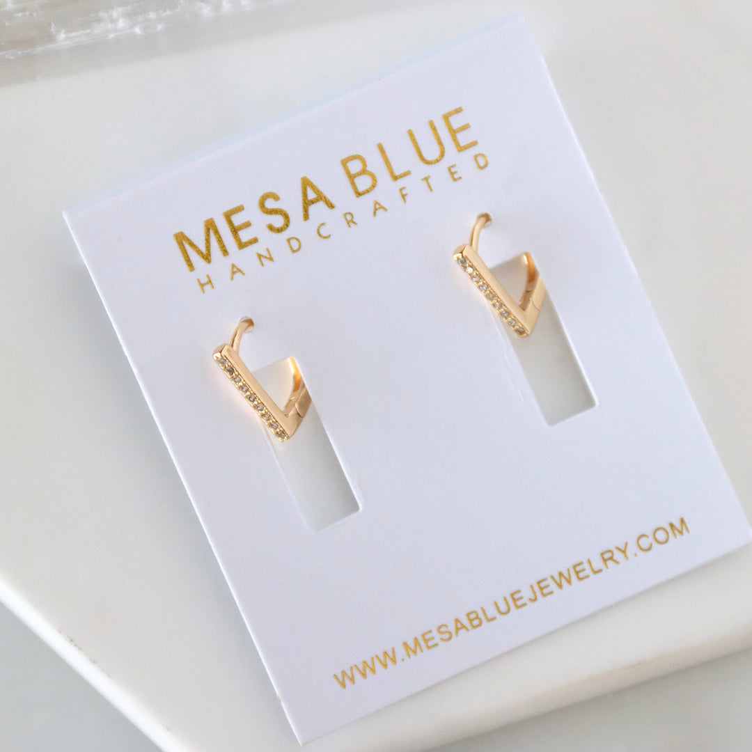 Gold hoop earrings on a Mesa Blue jewelry card with website information.