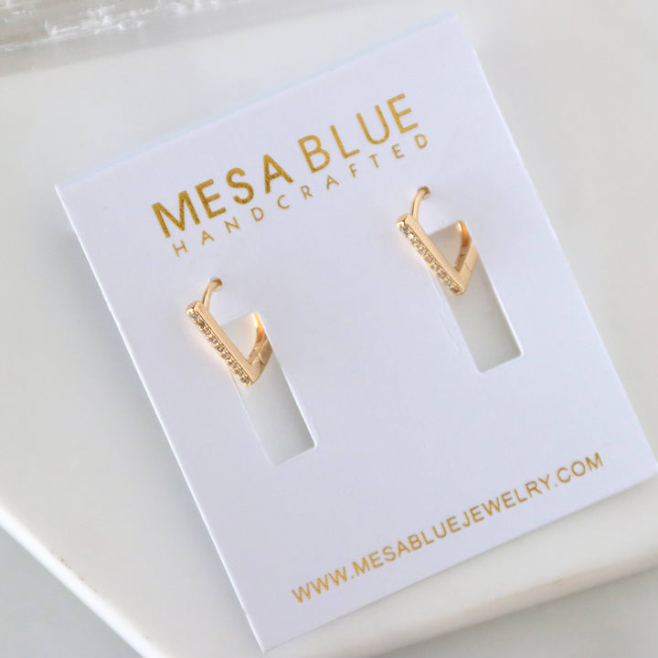Gold hoop earrings on a Mesa Blue jewelry card with website information.