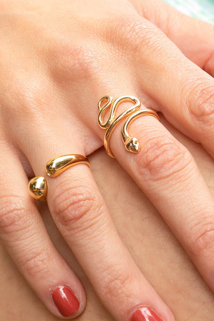 Close-up of a hand wearing two gold rings on a neutral background