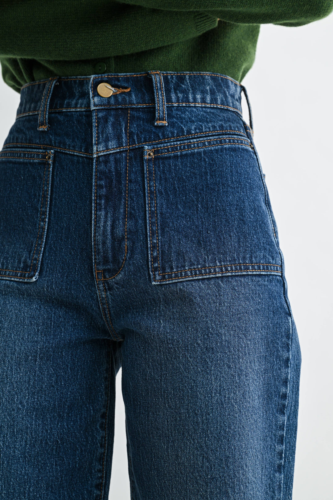 Blue high waisted jeans with a green sweater on a white background