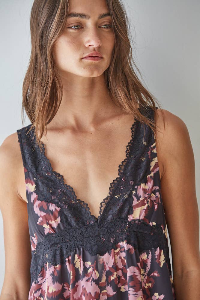 Woman wearing a floral dress with lace details against a plain background
