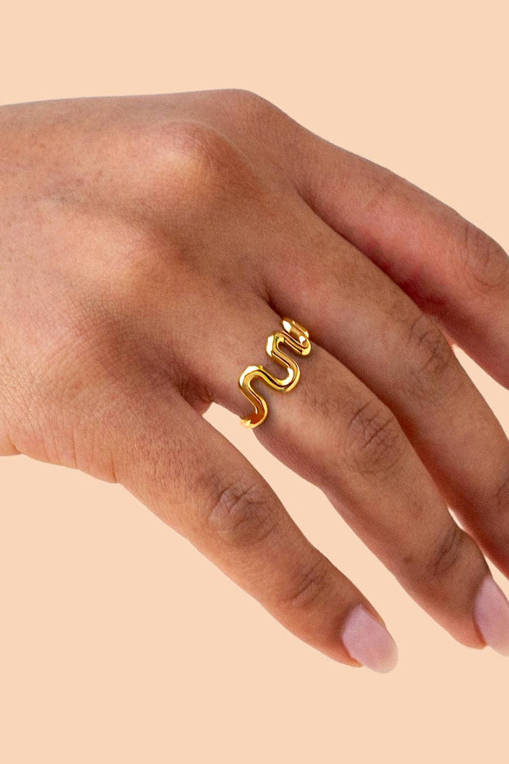 Gold ring on a hand against a beige background