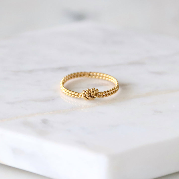 Gold ring with knot detail on a marble surface